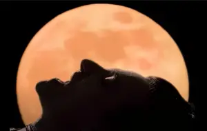 Imatge del videoclip Mysterious ways d'U2 en que es veu en Bono estirat amb la lluna de fons